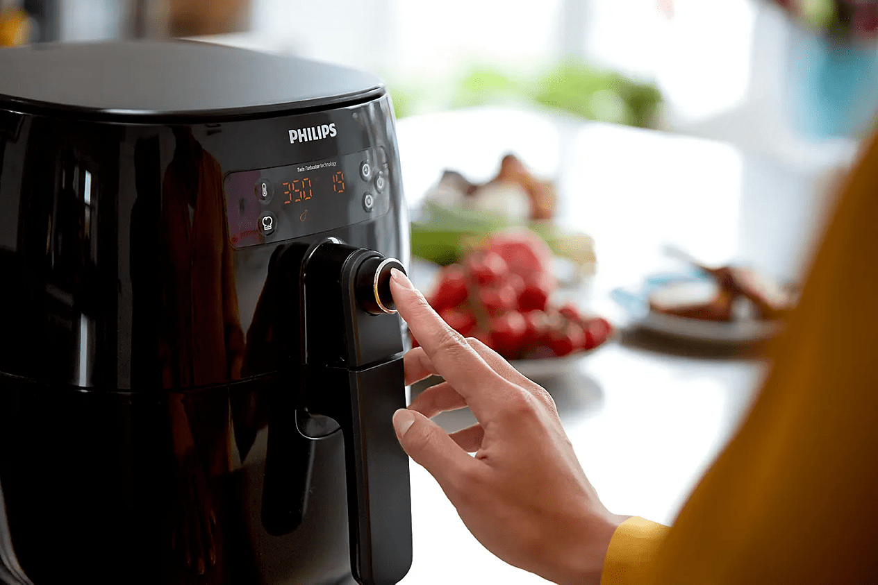 Philips Premium Airfryer HD9741/99 in Gebrauch, mit sichtbarem Digitaldisplay, zentralem Drehregler und geöffneter Schublade